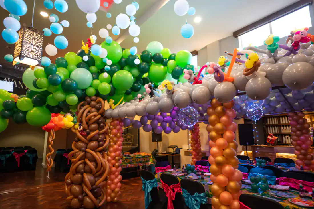 Balloon trees and colourful canopy for a rain forest first birthday build