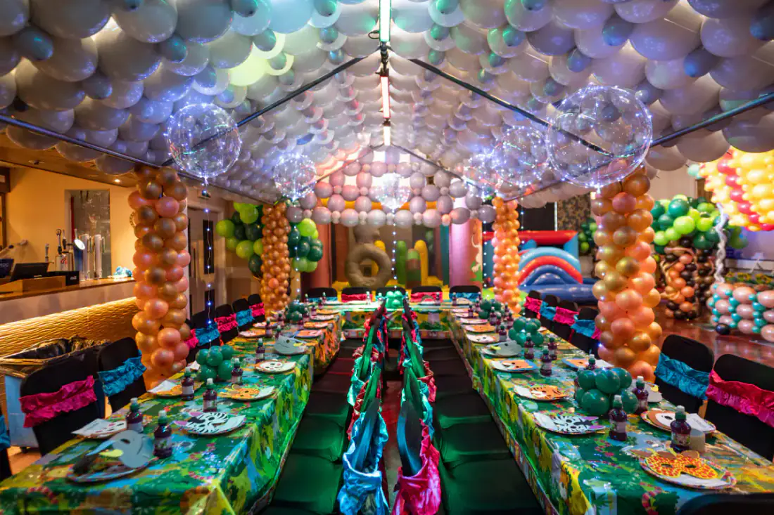 Rain forest birthday party room with ceiling balloons and themed table setup