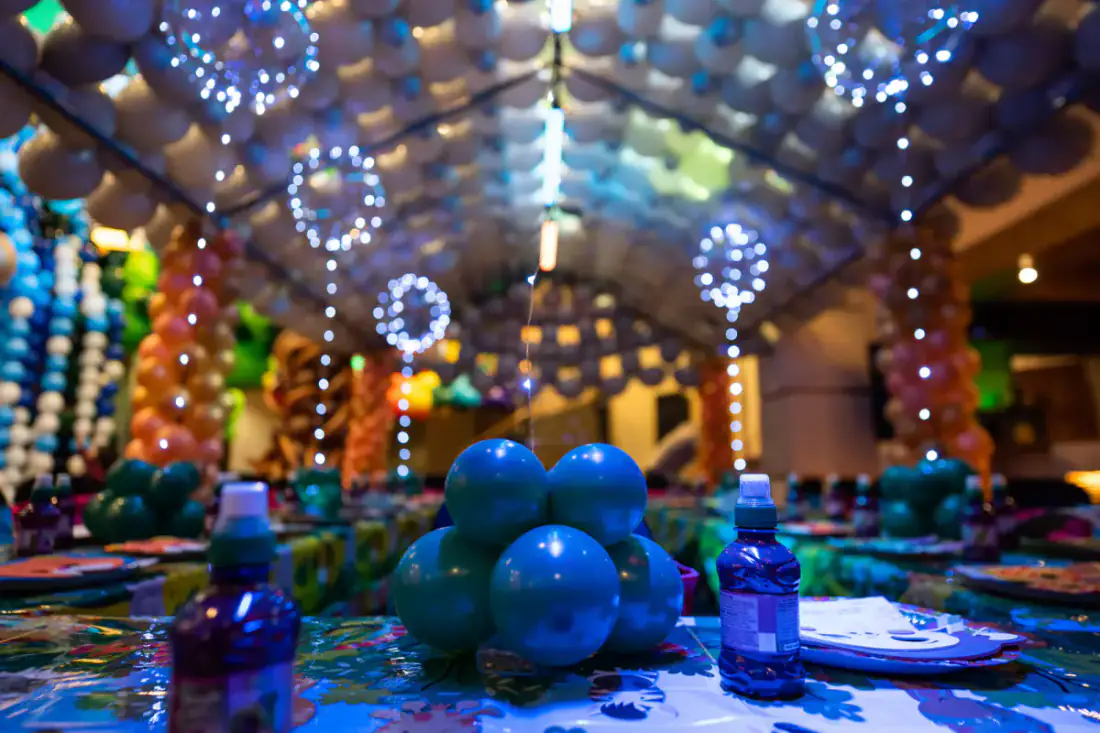 Themed party table setup under the rain forest balloon installation