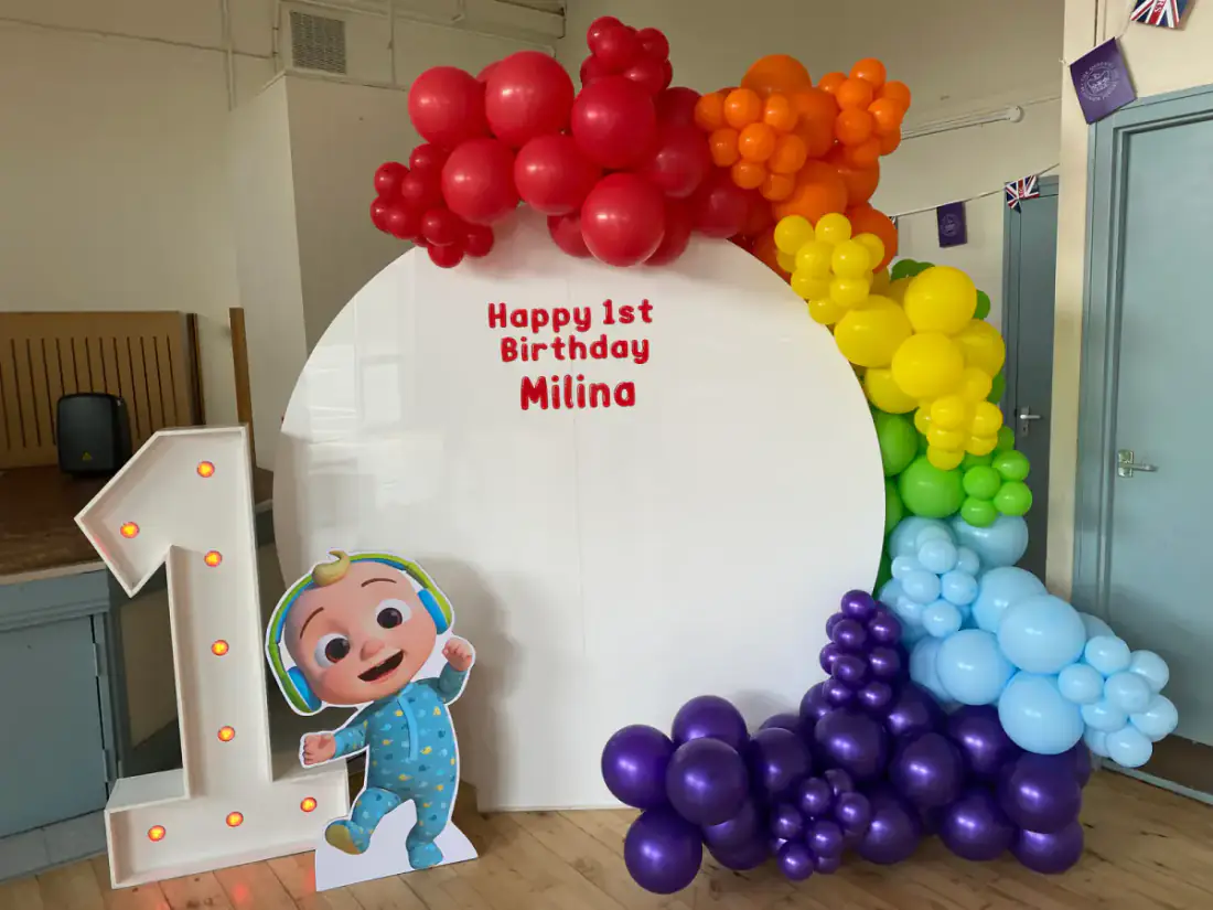 Rainbow first birthday backdrop with number one and character cutout