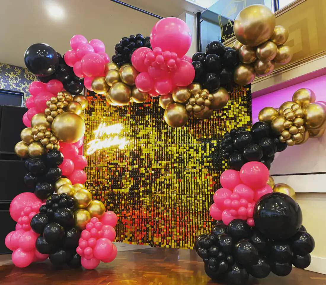 Pink black and gold birthday shimmer wall with balloon arch
