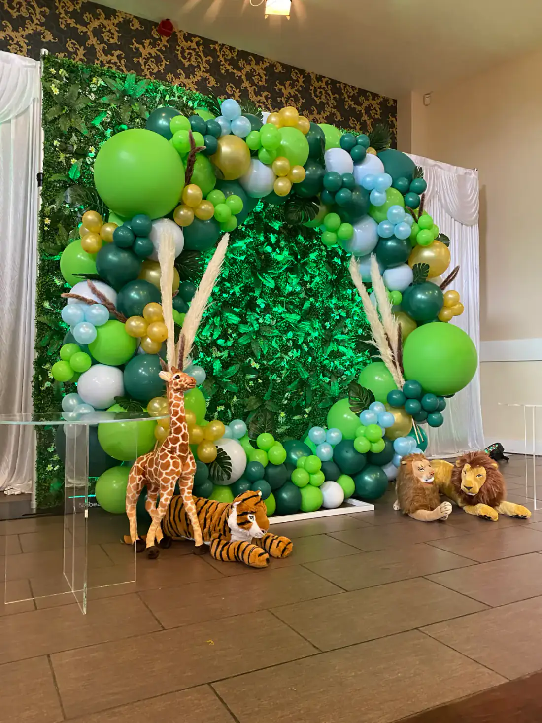 Green safari shimmer wall with balloon arch and animal props