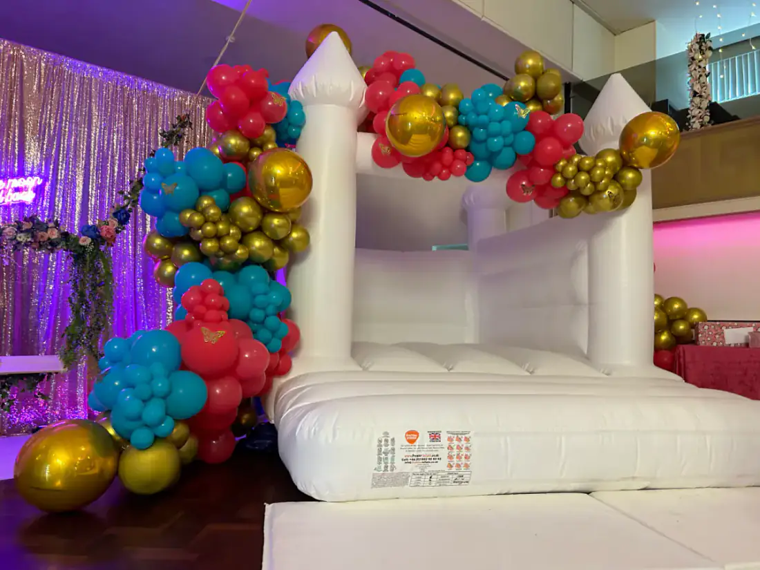 Colourful balloon garland over white soft play castle