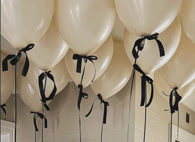 Ivory helium balloons floating at the ceiling with black bows and ribbons
