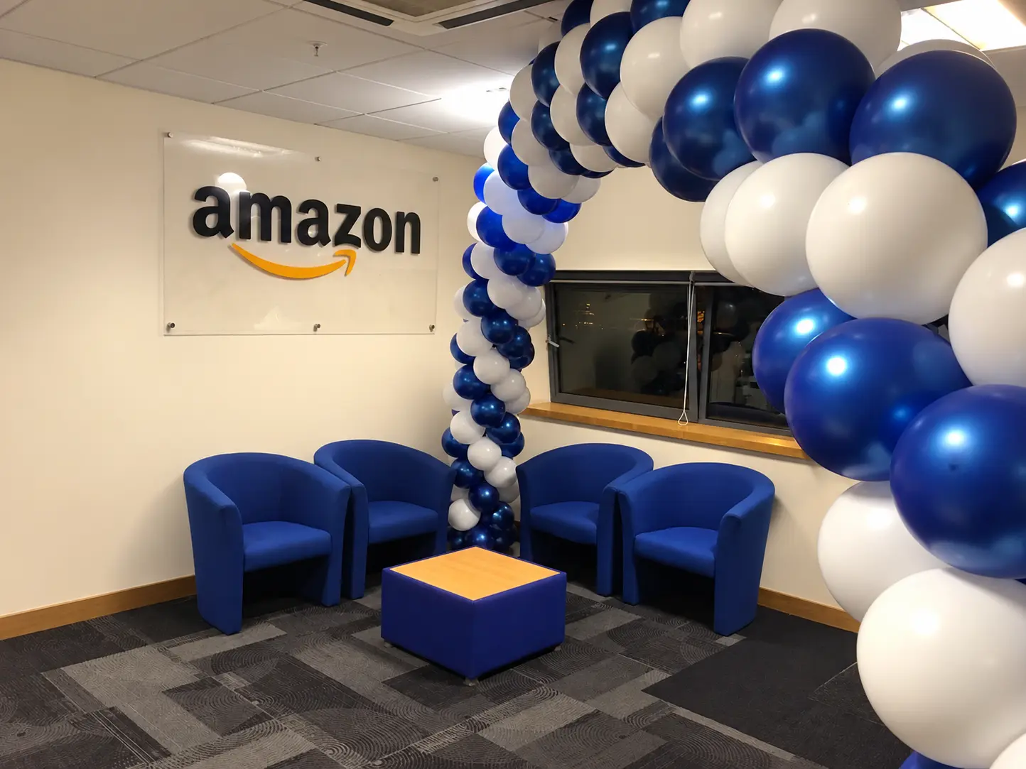 Blue and white branded balloon arch in an Amazon office reception area