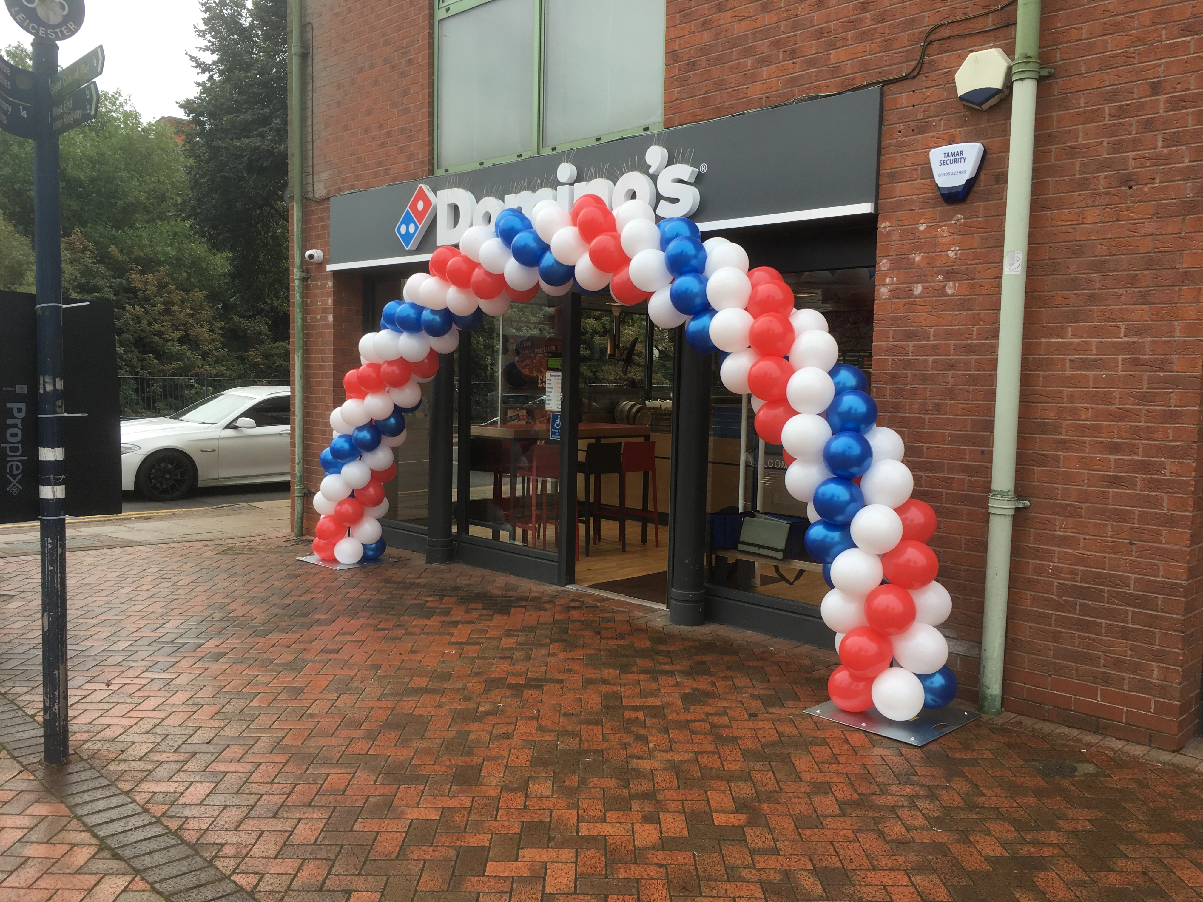 Red, white and blue balloon arch outside Domino's store
