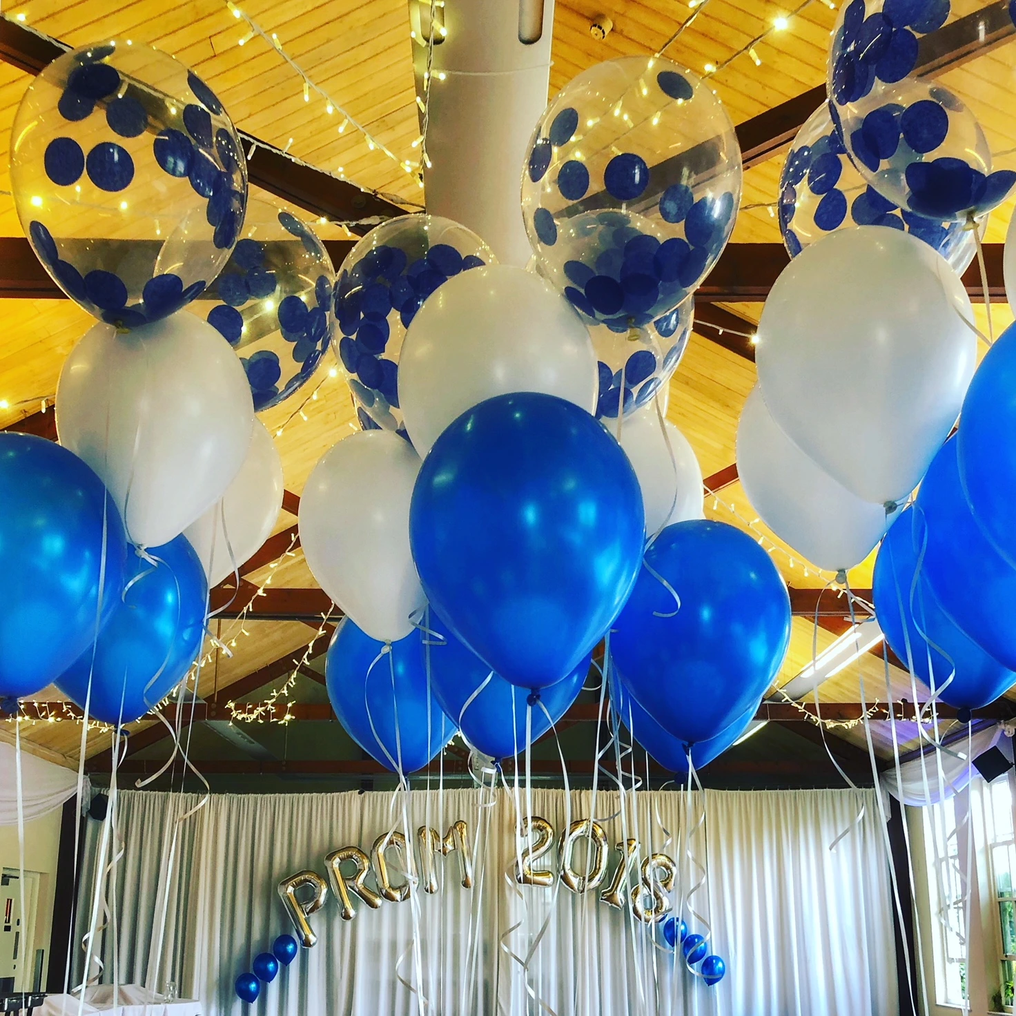 Blue and white ceiling balloon clusters for a prom venue
