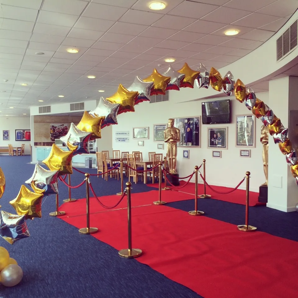 Red carpet prom entrance with balloon arch and rope barriers