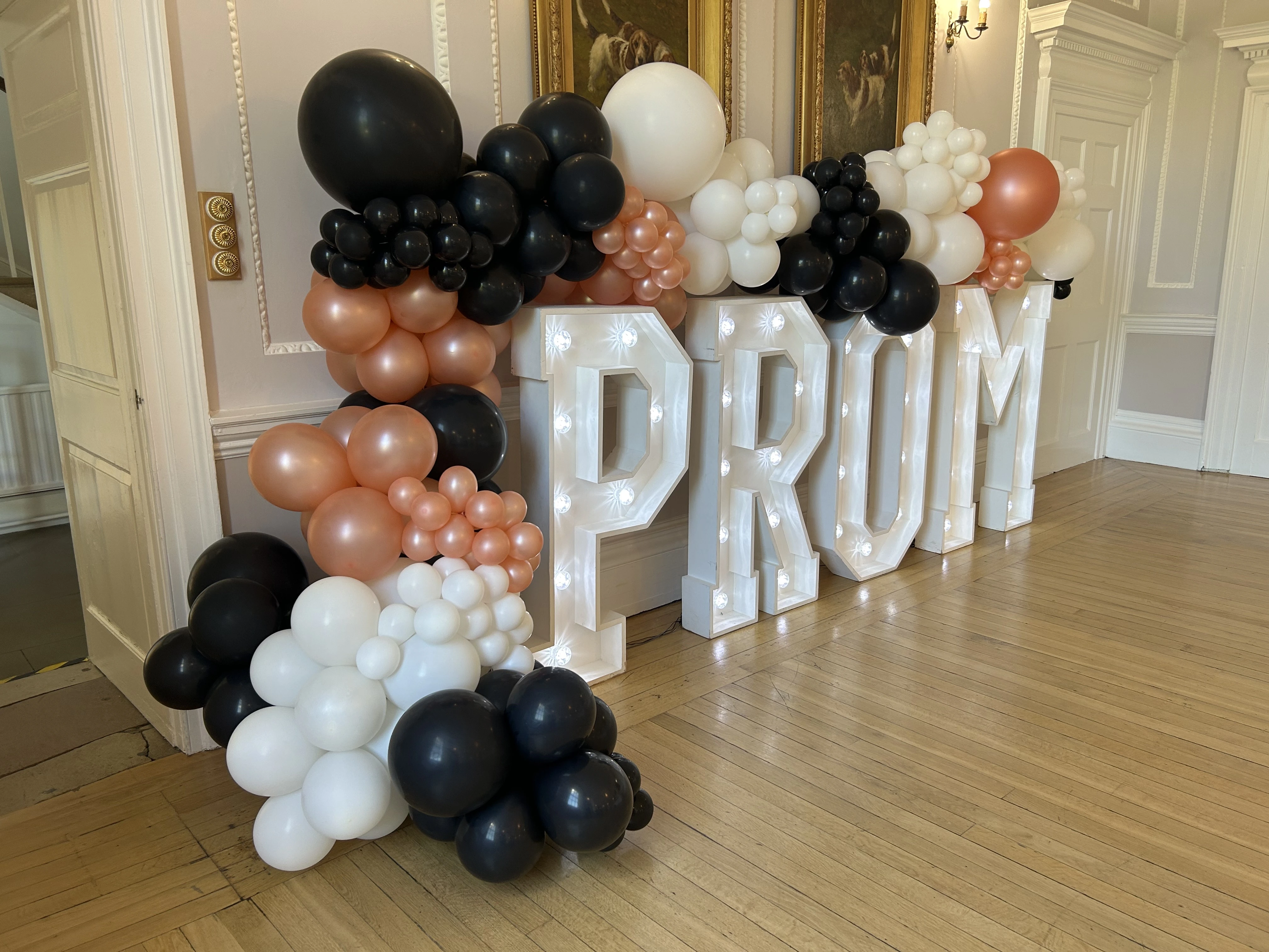 Copper, black and white balloon garland around light up PROM letters