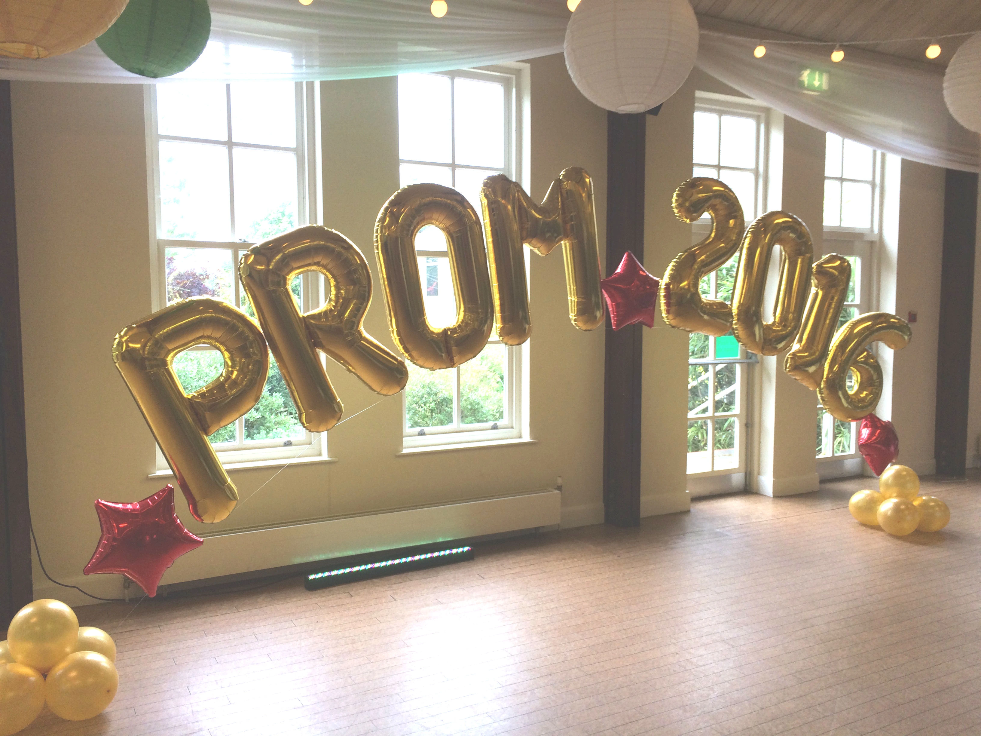 Gold foil PROM balloons displayed by windows at a prom venue